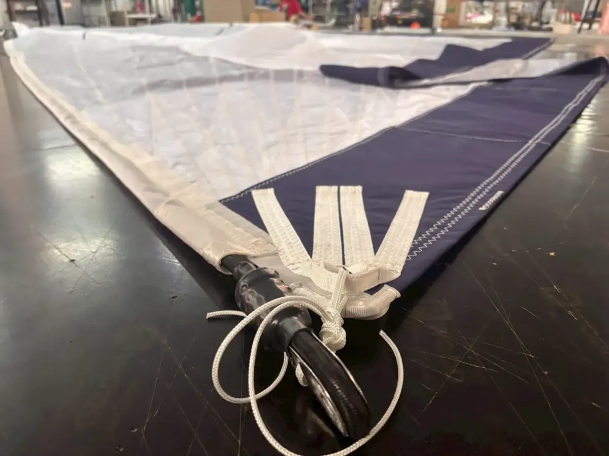 Tack of a navy and white code zero with webbing straps gathered onto a torsion rope end fitting and swivel
