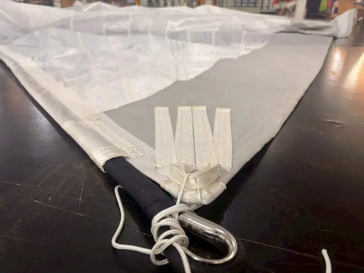 Webbing straps sewn onto a black torsion rope with a stainless thimble and lashing at a code zero tack