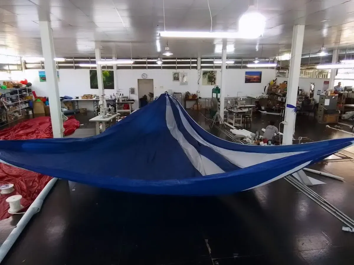Sailmakers holding a blue and white asymmetric spinnaker open across the loft floor